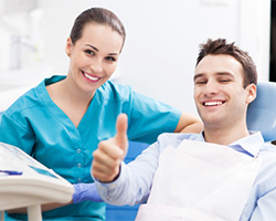 Smiling man in dental chair giving thumbs up