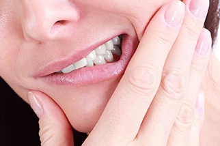 A woman holding her cheek in pain