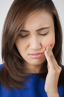 woman holding cheek in pain